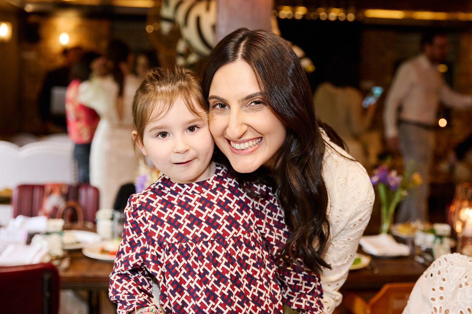 A lady with a little girl smiling during a Christening celebration in London.