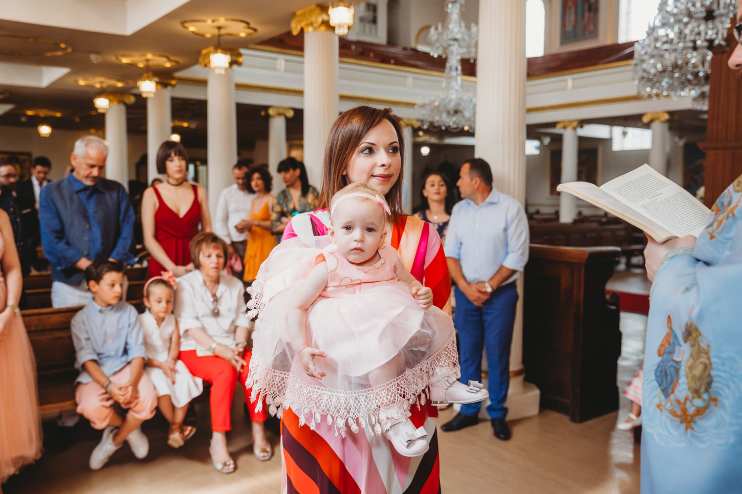 A godmother holding a little girl during her christening reading.