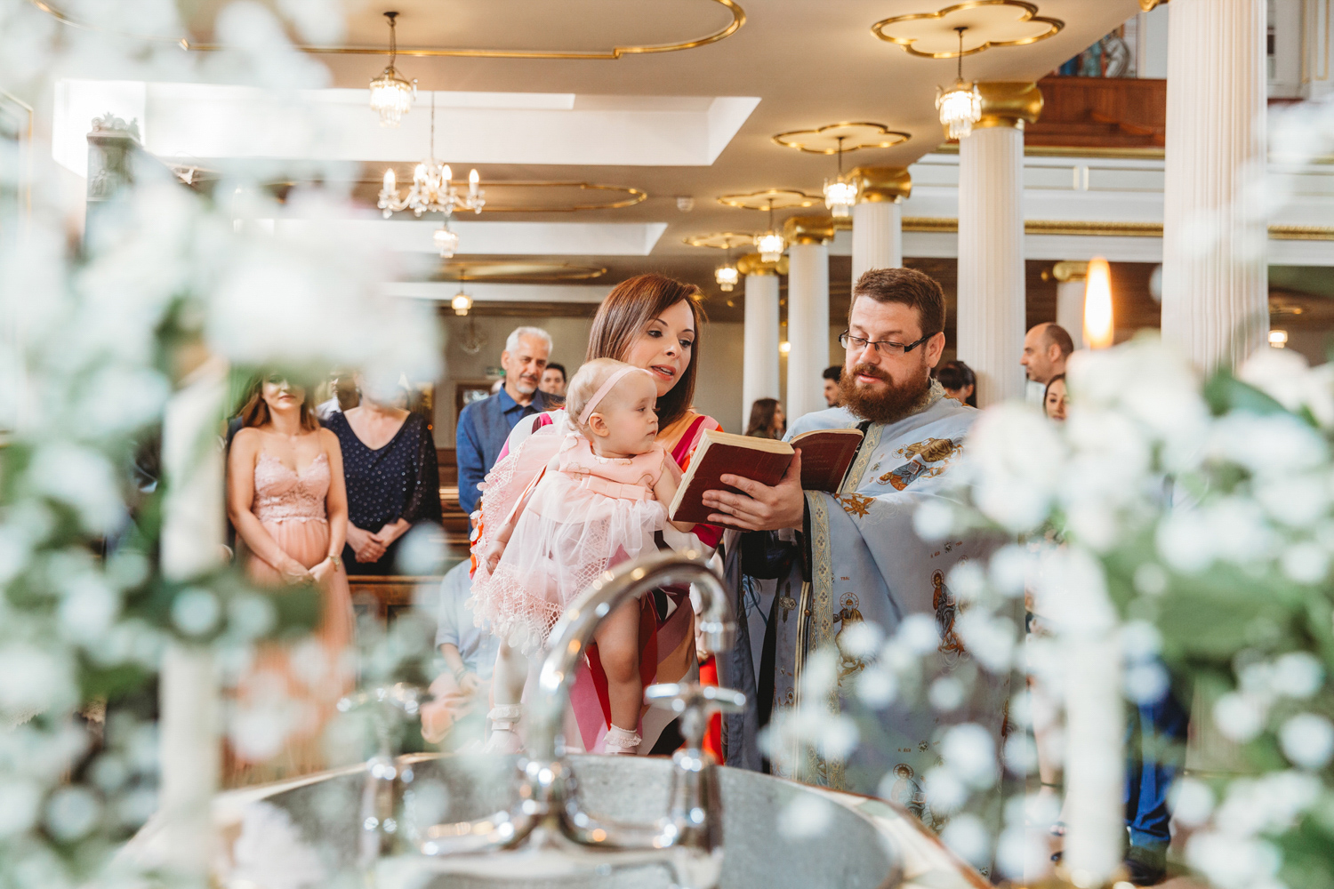 A godmother holding a little girl during her christening reading.