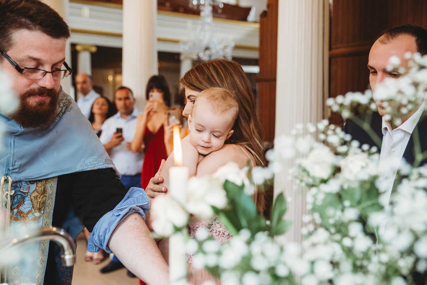 Little girl about to be christened held by her mum.