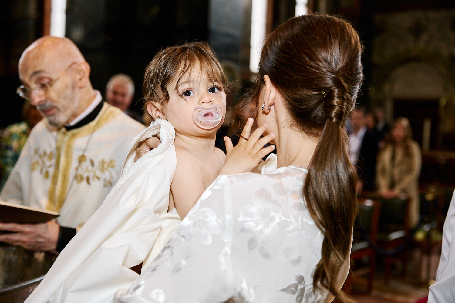 Little boy looking at the camera while waitign to be christened.