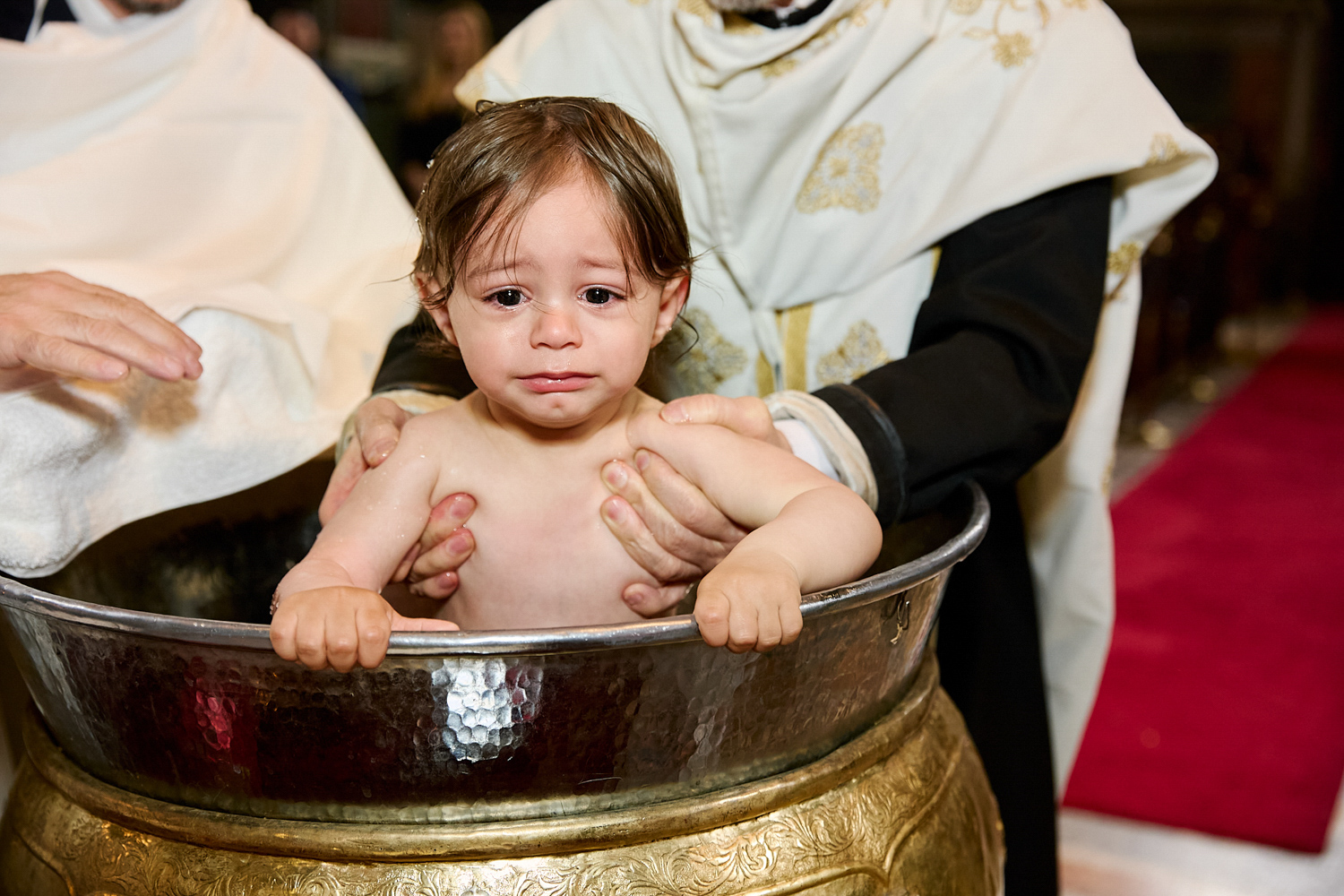Little boy crying while he's being baptised.