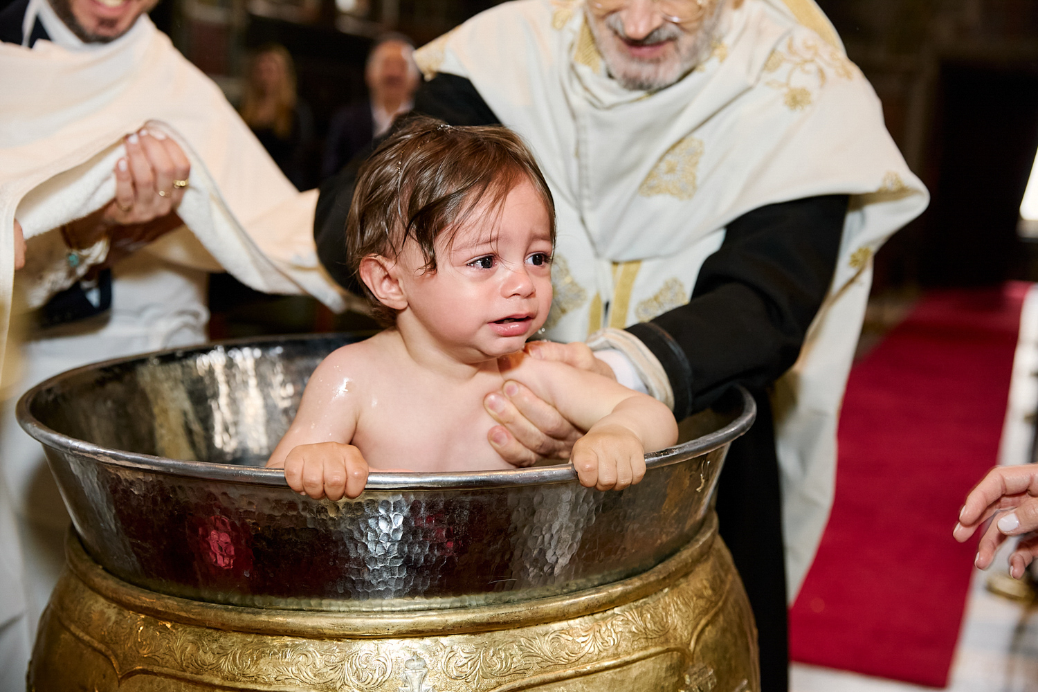 Little boy crying while he's being baptised.