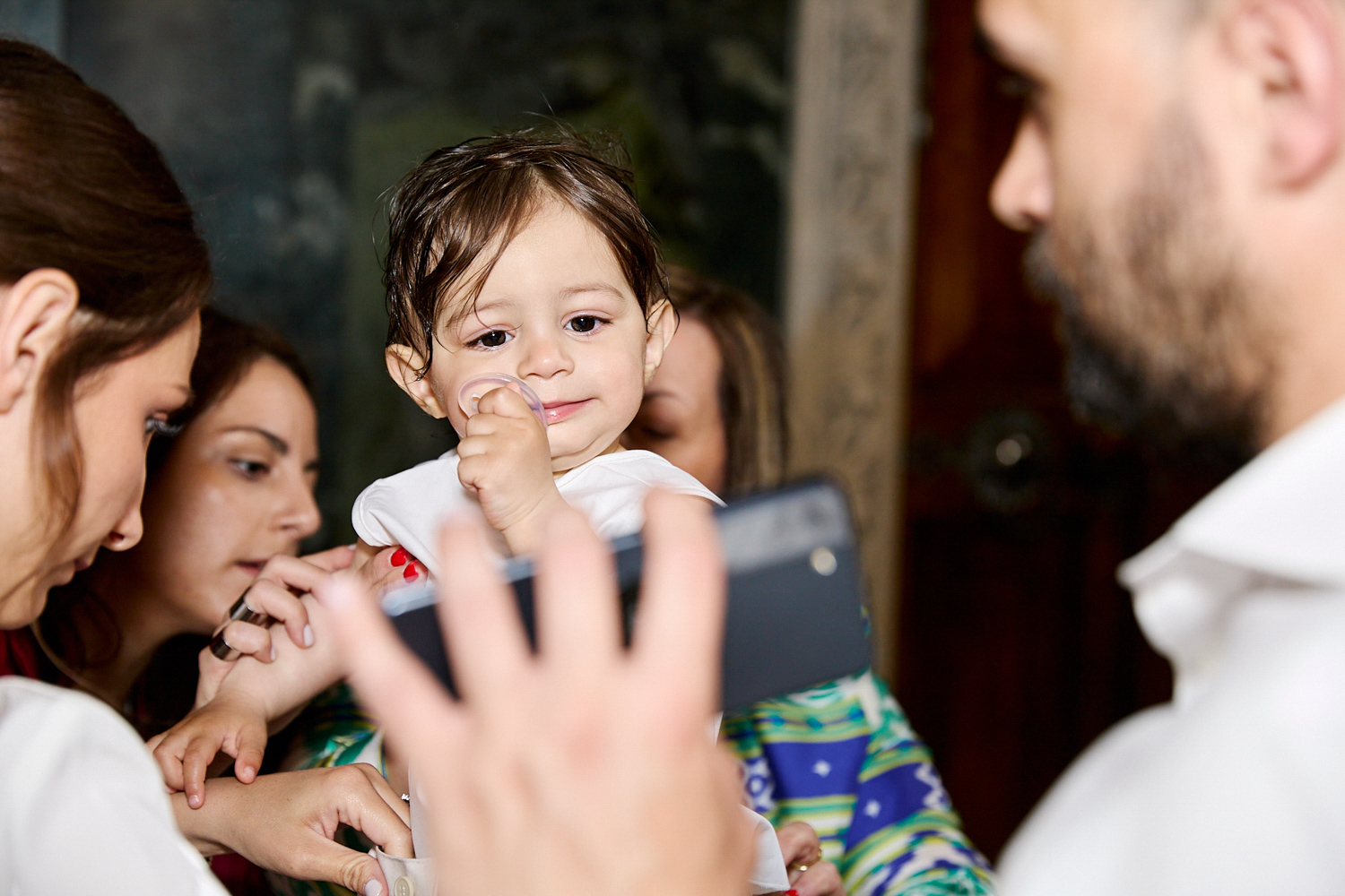 Little boy watching something on a mobile phone while waiting to be christened.