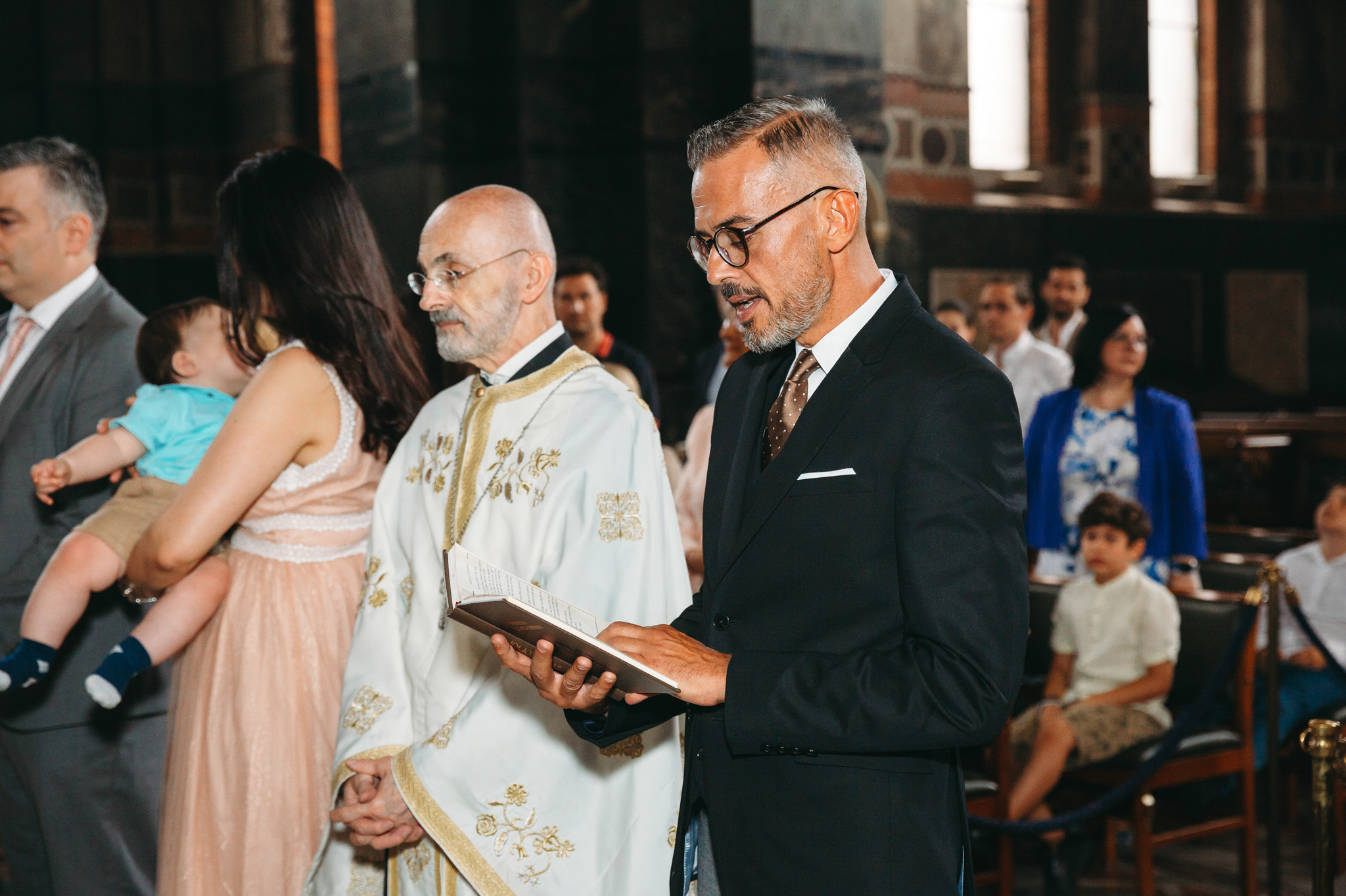 Godfather reading some blessings during a baptism ceremony in church.