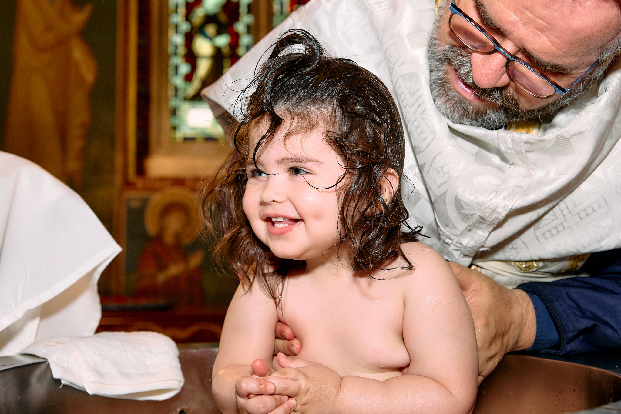 A little toddler being happy and smiling during her baptism.