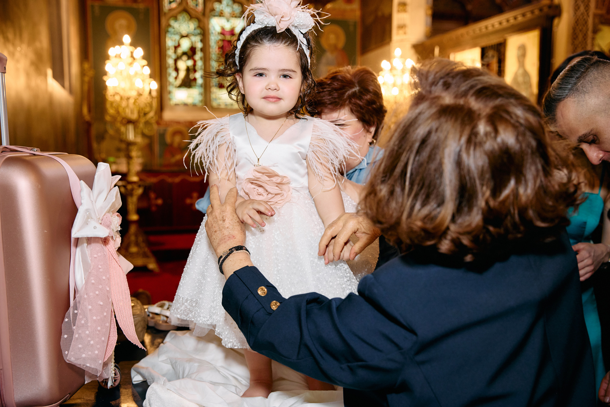 Little girl standing up in her christening dress hel by her grandmother.