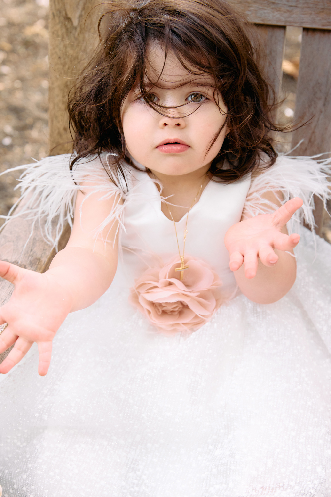 Little girl in her white dress sitting on a bunch outside, after her chirstening.