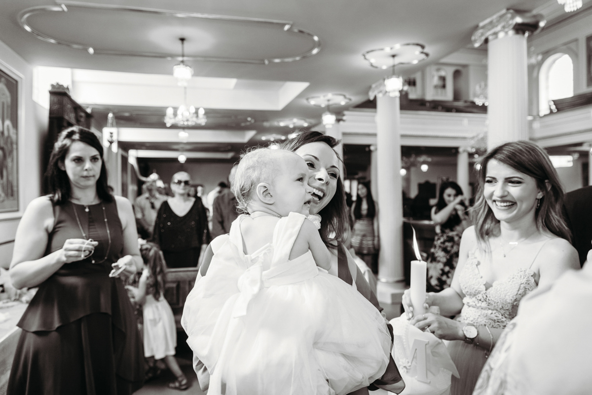 A documentary style photo of a godmother smiling during a christening.