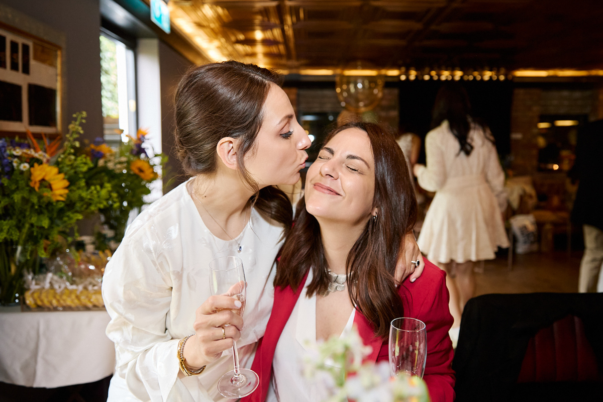 A lady kissing another lady on her cheek during a christening dinner at a venue.