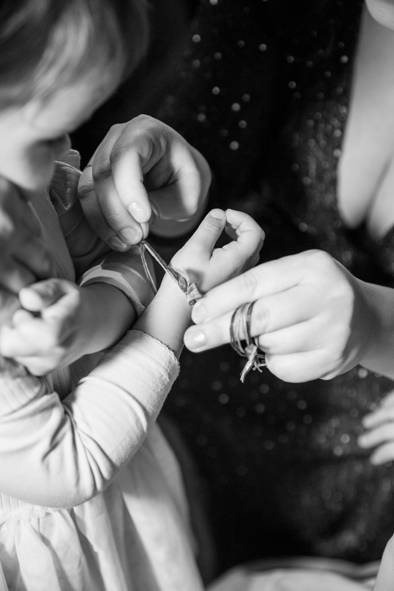 mum puts christening bracelet on little kids wrist during a baptism ceremony in London