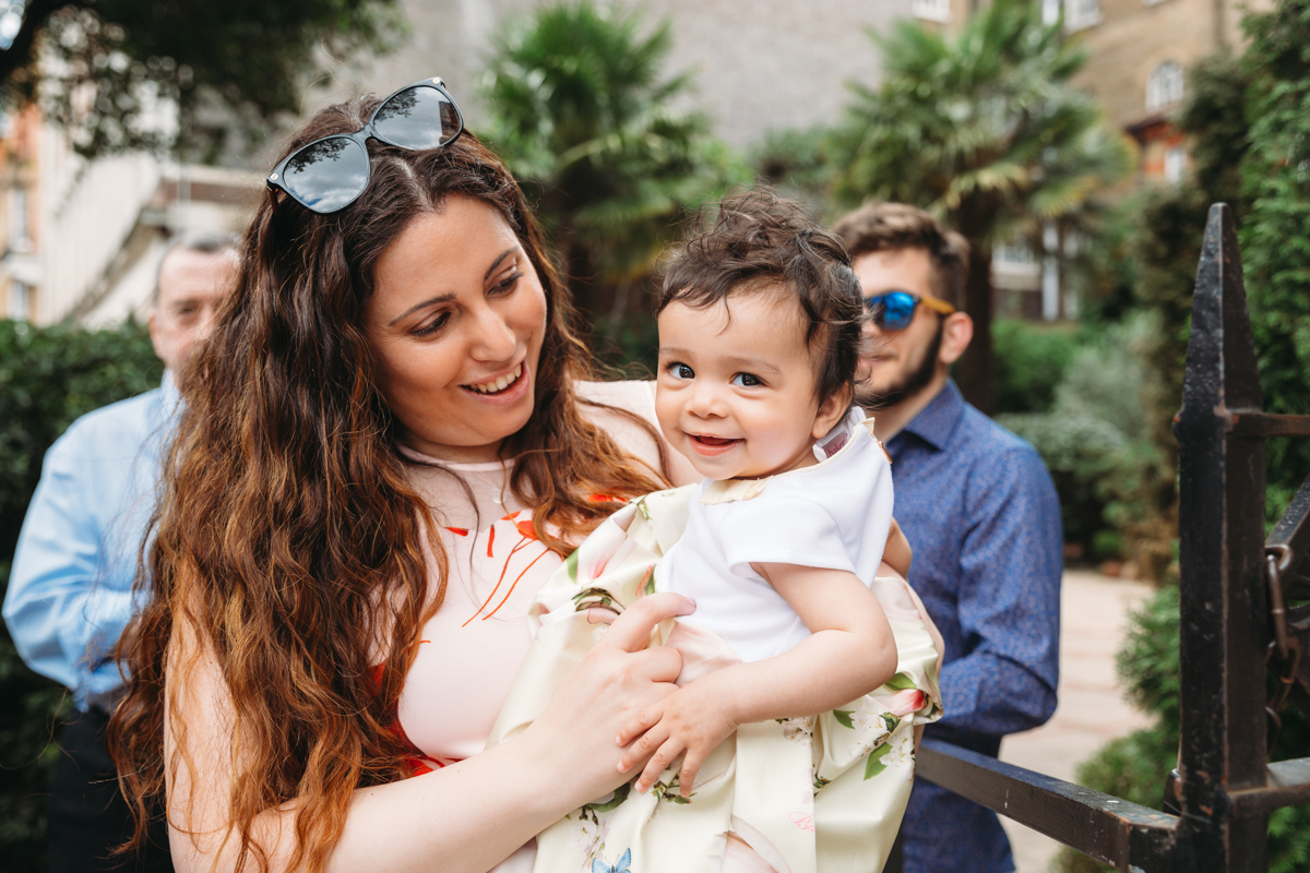 Mum holding her baby who was just christened, outside a church.