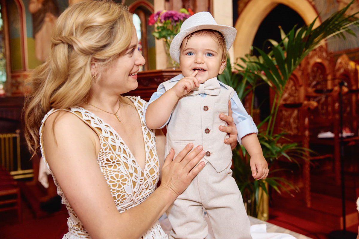 Godmother holding the newly christened boy in his new clothes.