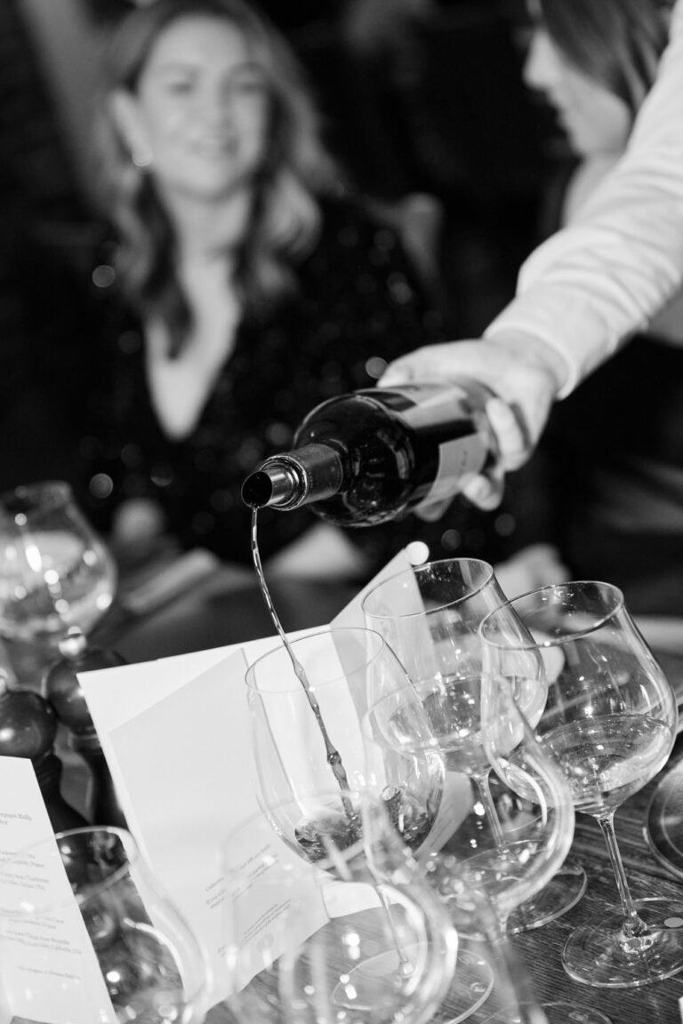 a waiter pouring red wine in glasses during an event in London