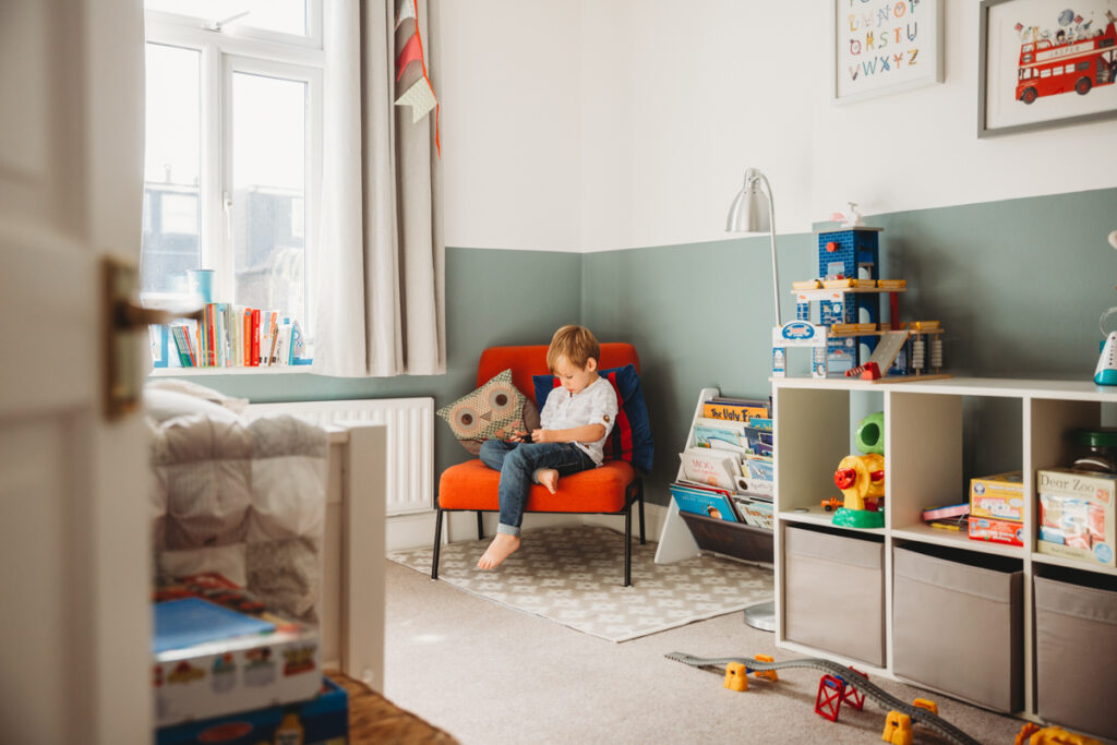 little boy sitting on a chair in his room reading
