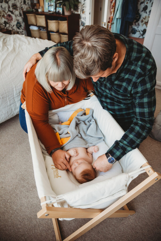 Parents cuddling their newborn baby in his cot, holding lovingly each other.