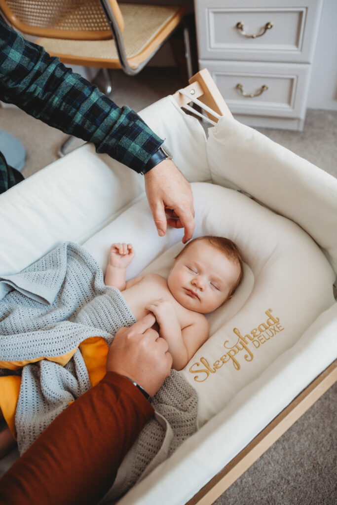 Parents cuddling their newborn baby in his cot, holding lovingly each other.