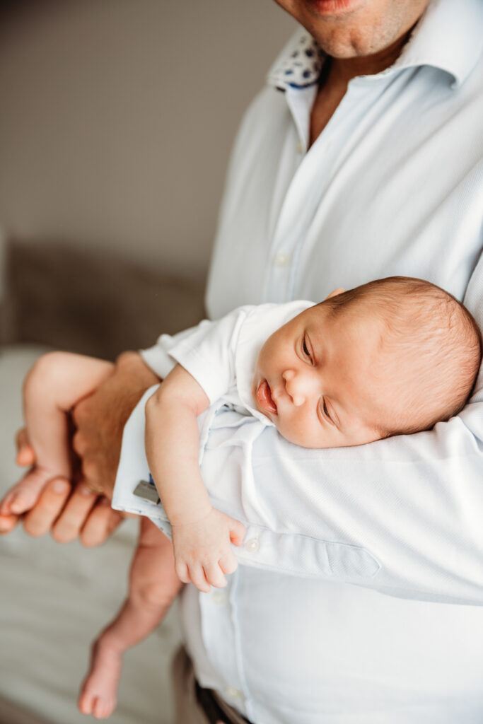 Baby held by his dad close to the window. Beautifu soft natural light.