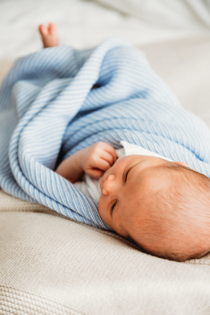 Baby wrapped in blue blanket on his mum's bed.