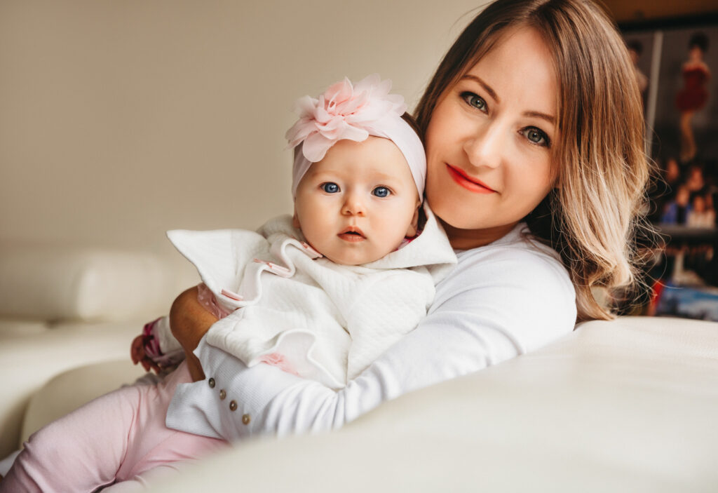Mum smiling at the camera while holding her pretty baby girl.