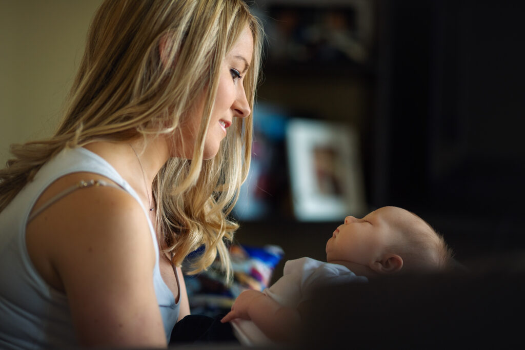 Mum looking at her newborn baby smiling while baby is asleep.