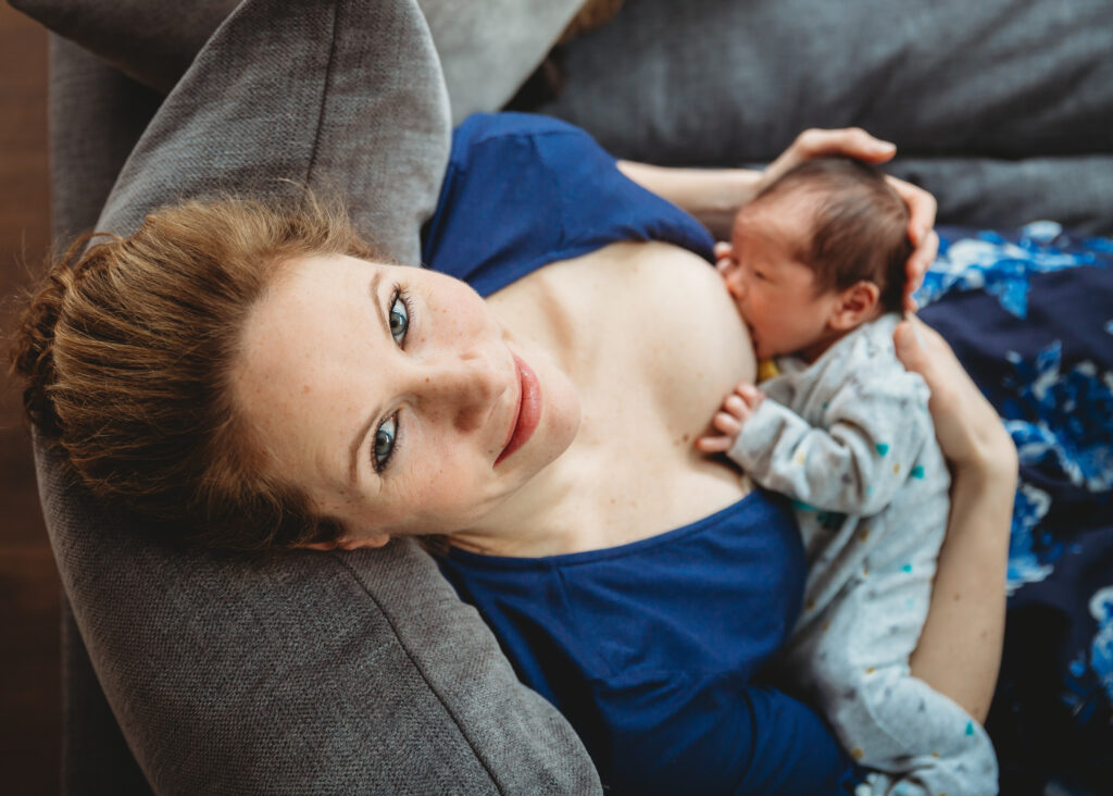 Top view of a mum breastfeeding her newborn baby. Mum is looking up at the camera.