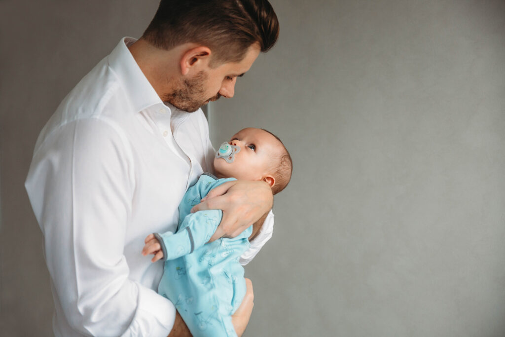 Dad holding his baby while baby is staring at him.