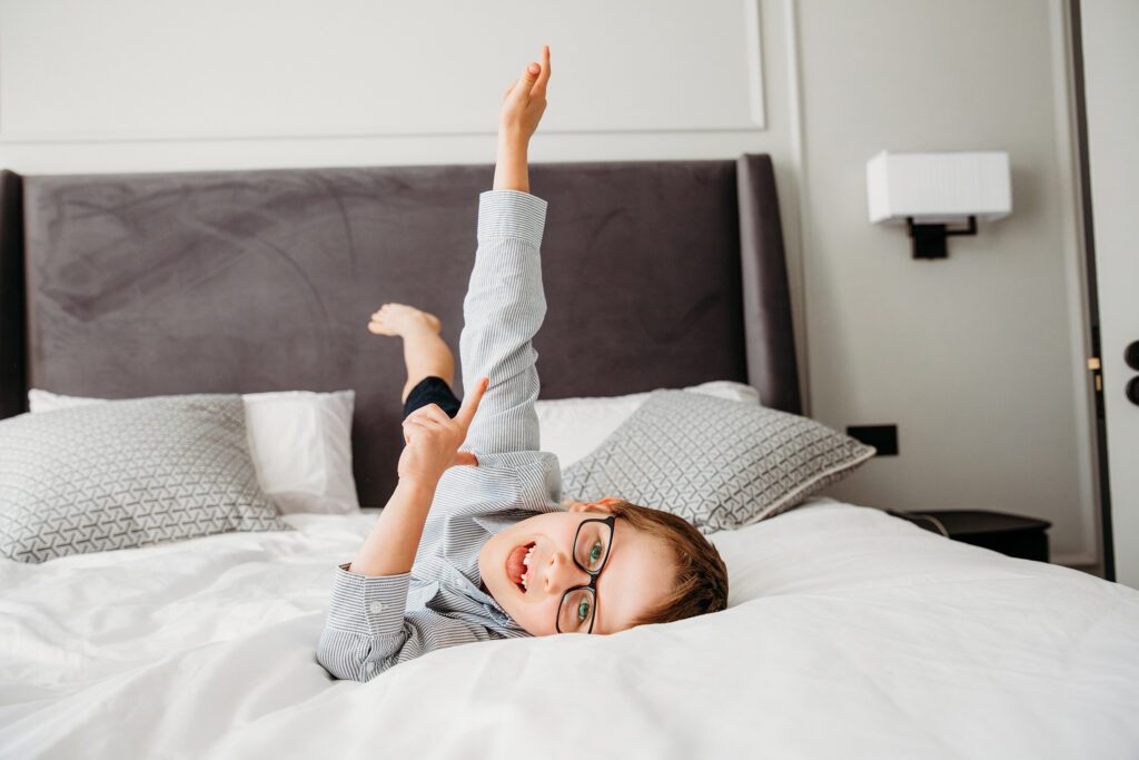 Little boy making silly facew while lying in bed.