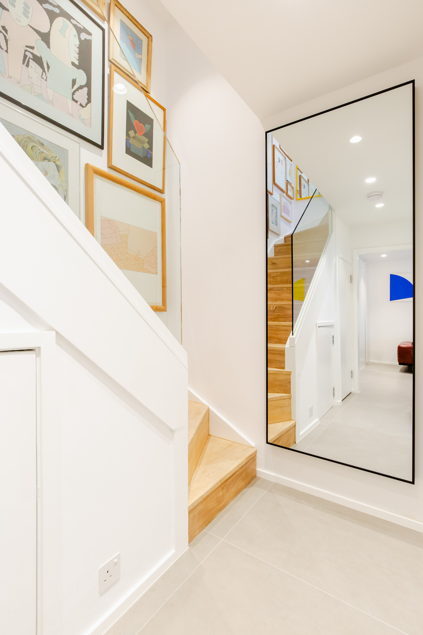 A mirro by the staircase reflecting the whole staircase.