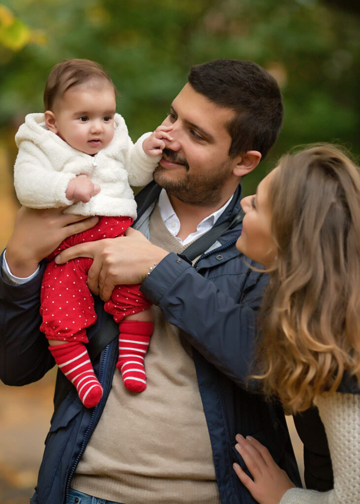 Mum and dad looking at their baby in a park in Northern London.