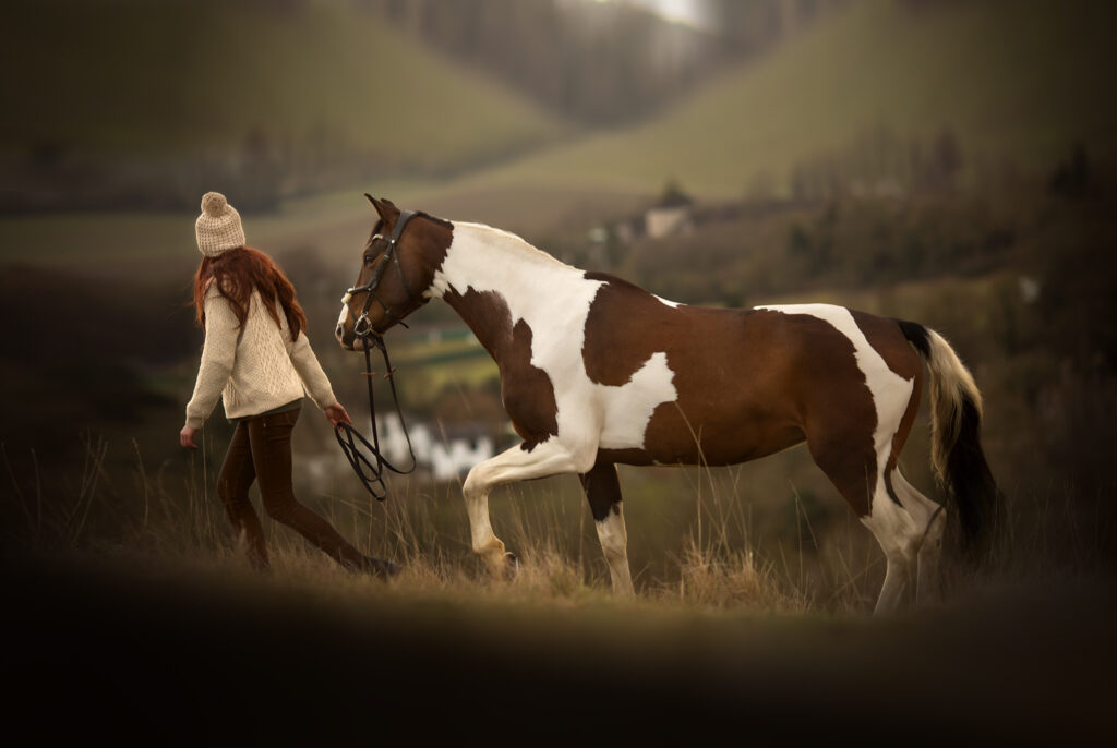A girl walking her horse on a hill with beautiful views on a cold winter's day in Surrey.