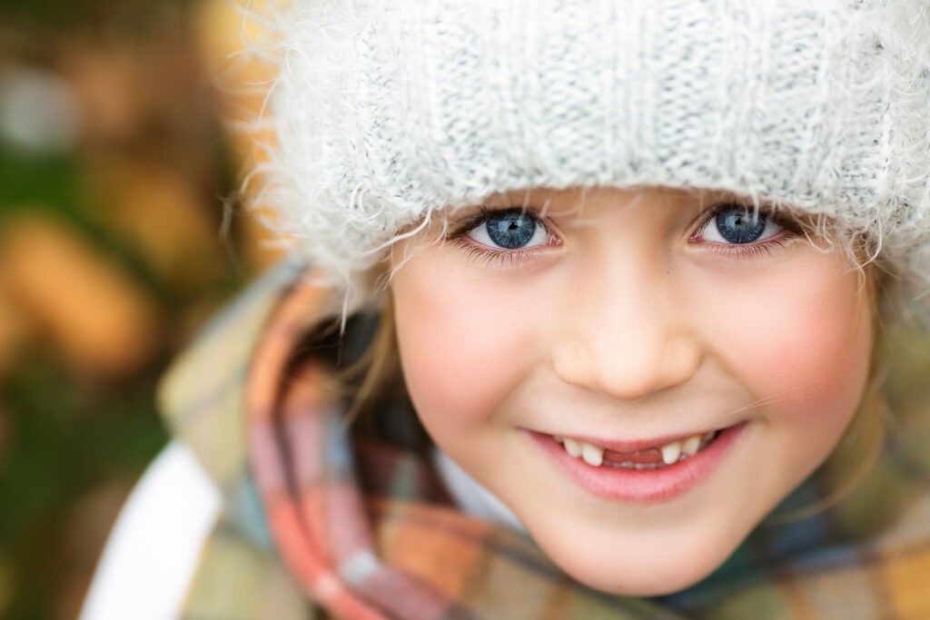 Close up of a little girl smiling at the camera. She has amazing blue eyes.