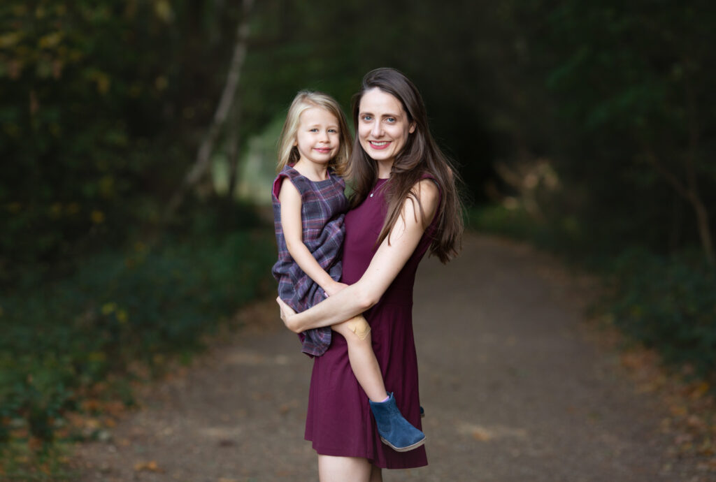 A mum holding her girl and posing for a photo in summer time at Wimbledon Park.