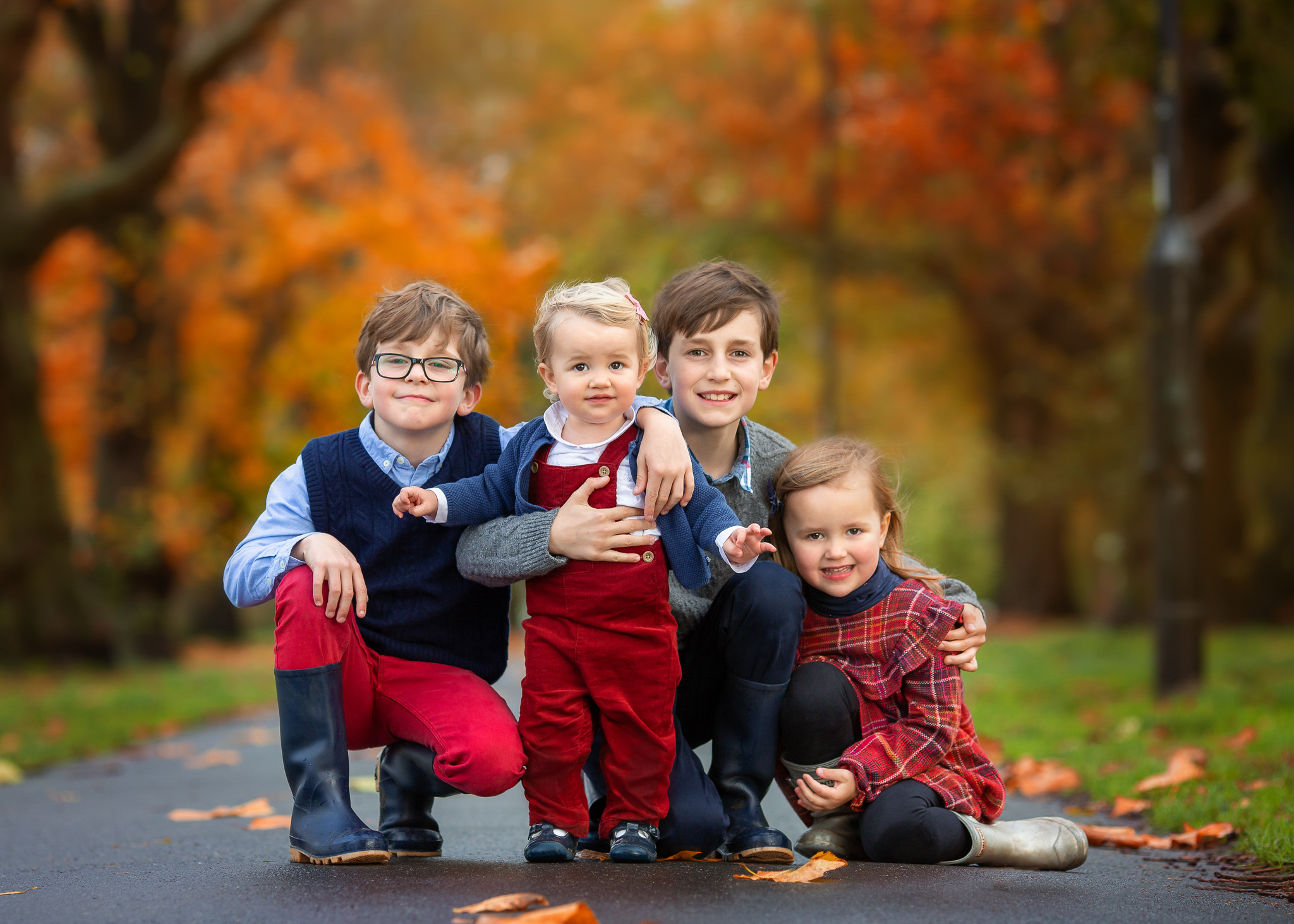 3 kids and a baby posing for a photo hugging each other in Wandsworth Common.