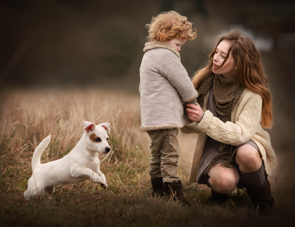 A girl trying to comfort her little brother while a little puppy is passing by in a cold winter day.